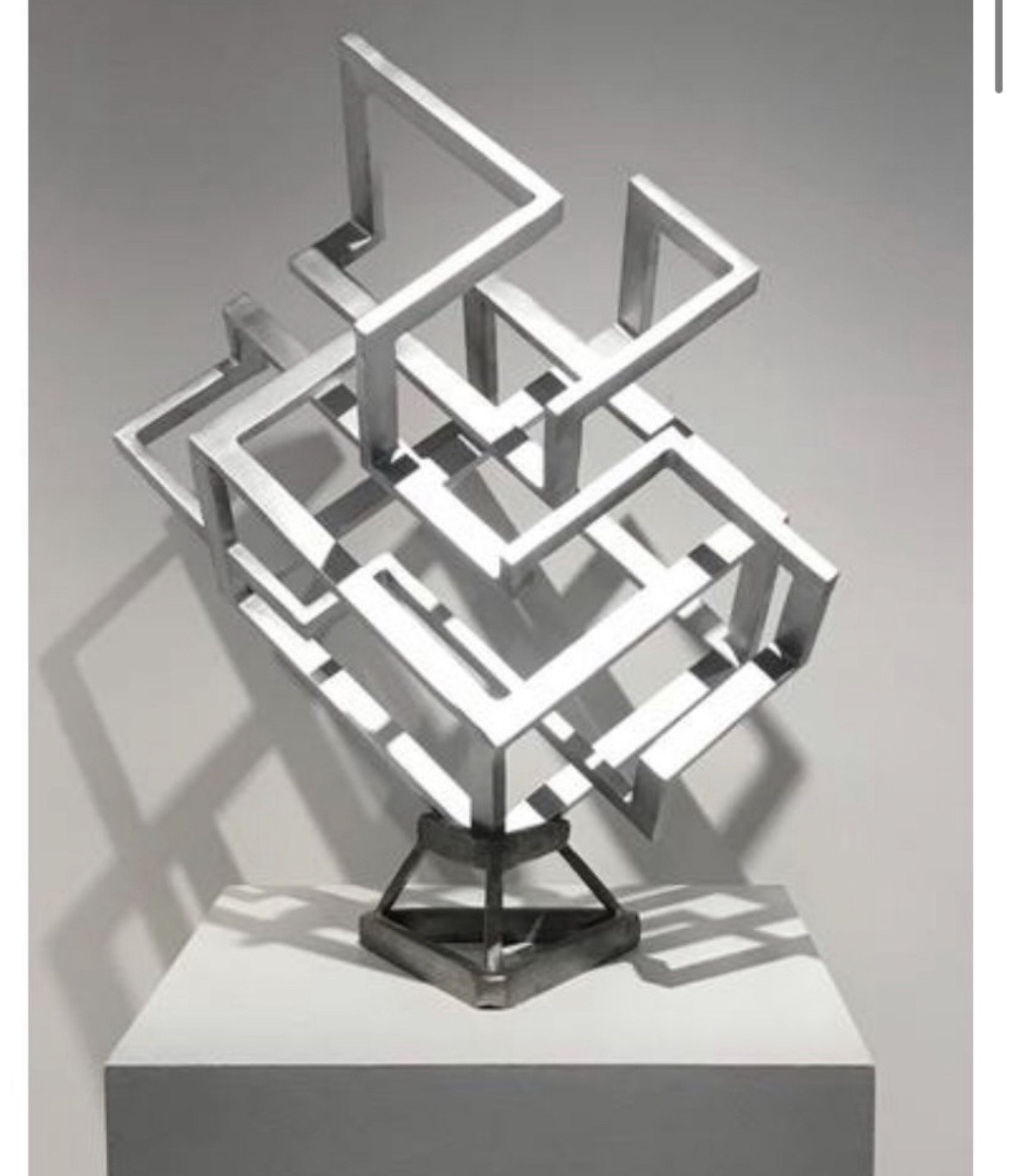 Complex 1, a stainless steel sculpture of intersecting geometric bars radiating from a central box on a triangular stand