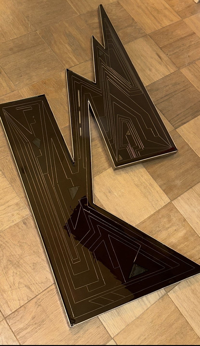 Skyline Noir, a jagged stainless steel and stained wood wall sculpture with a resin-cast sacred-geometry inlay