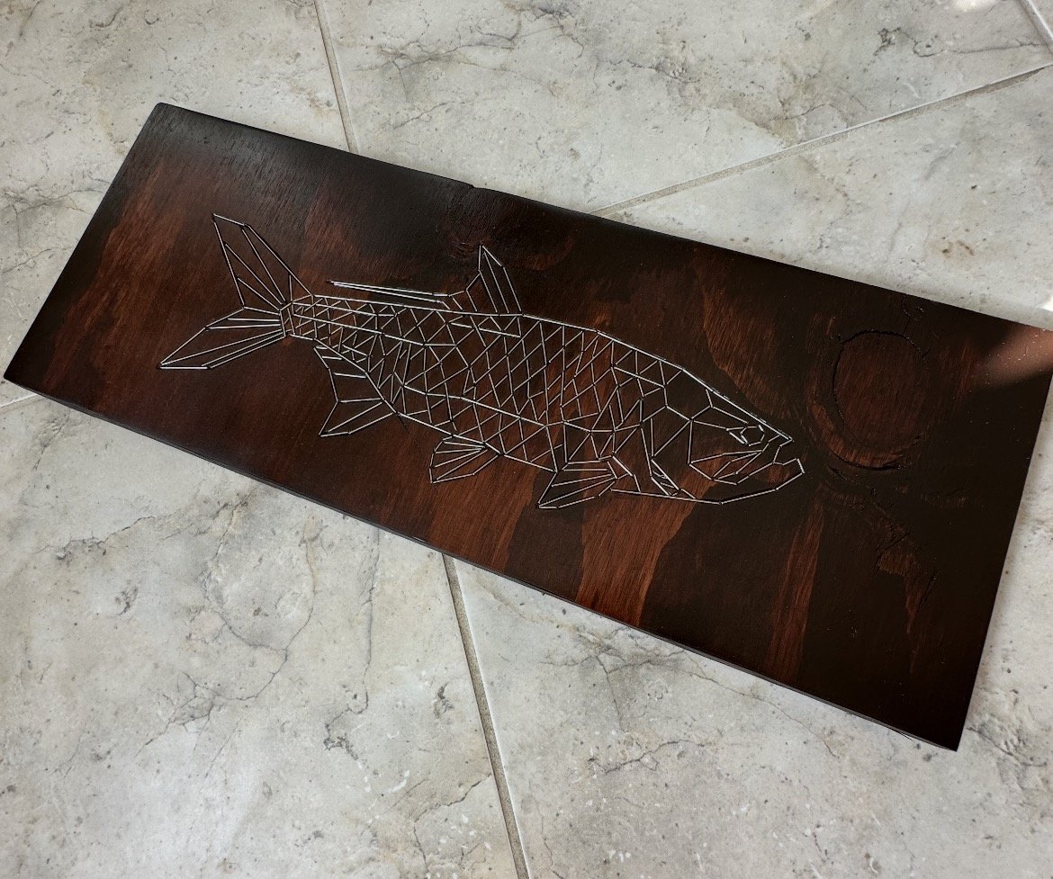 Tarpon, a stained wood panel engraved with a tarpon and inlaid with stainless steel rod